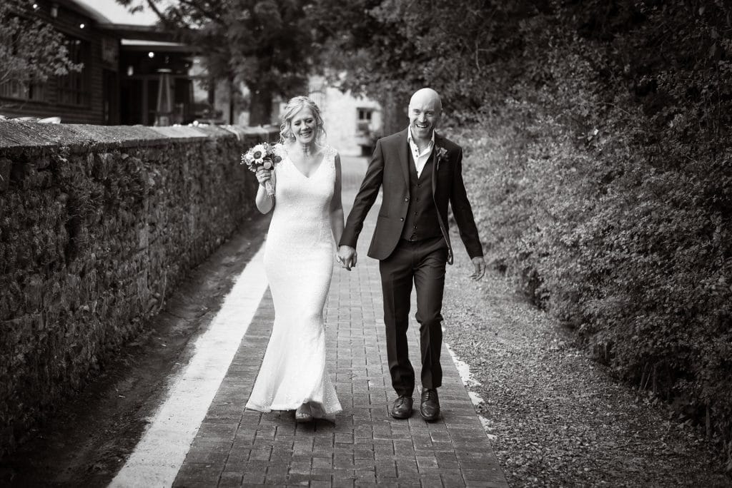 Laughing couple walking to Village Barn Wedding Sanctuary