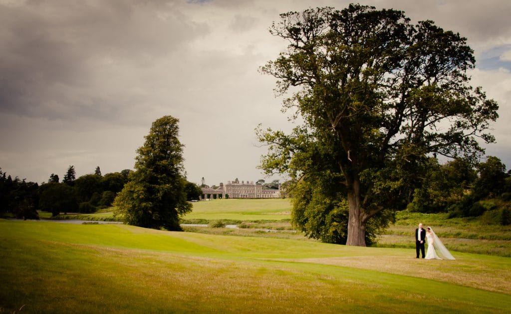 Weddiing couple walking with Carton House in background