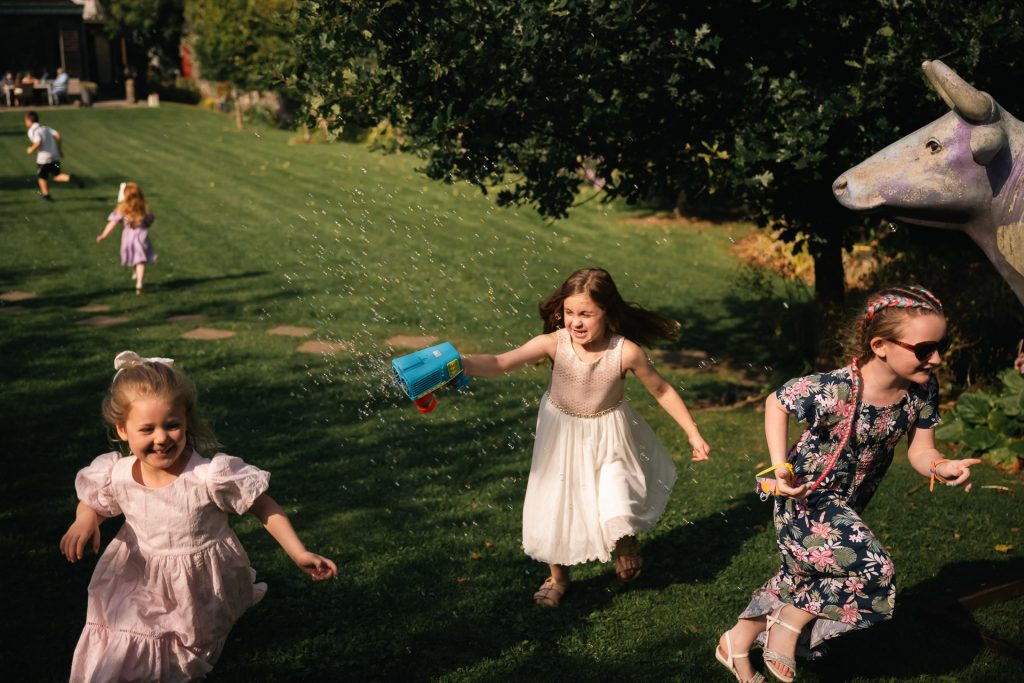 Wedding children running with bubble gun at the village barn